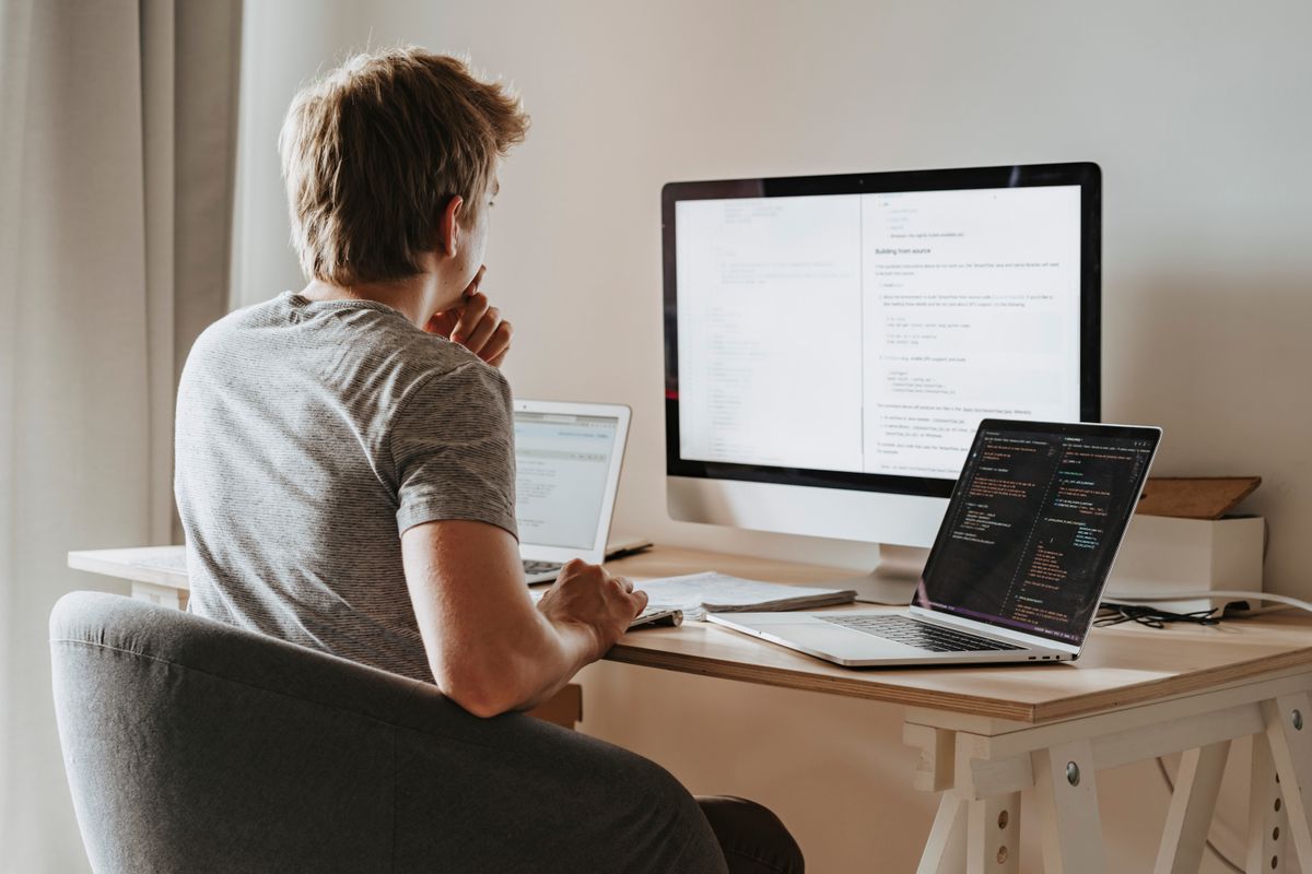 A developer working across code on multiple screens