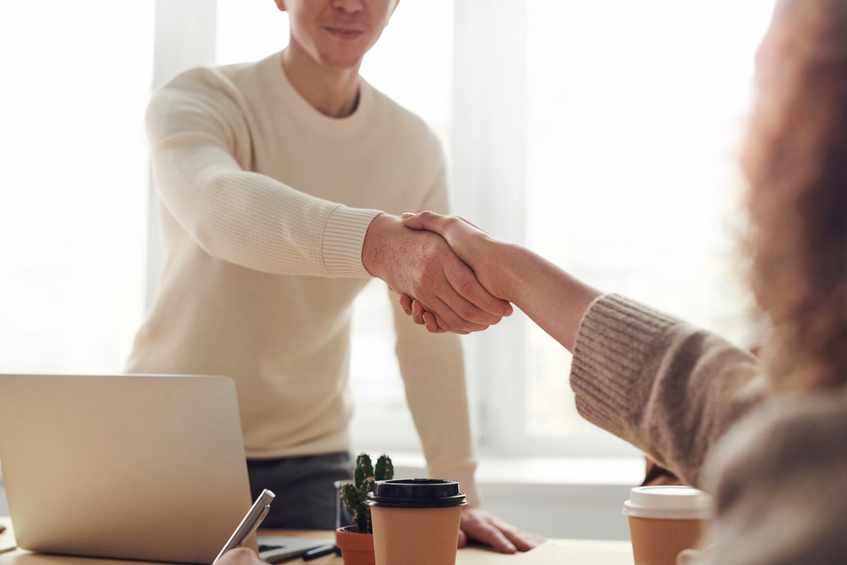 A client and partner shaking hands over a laptop