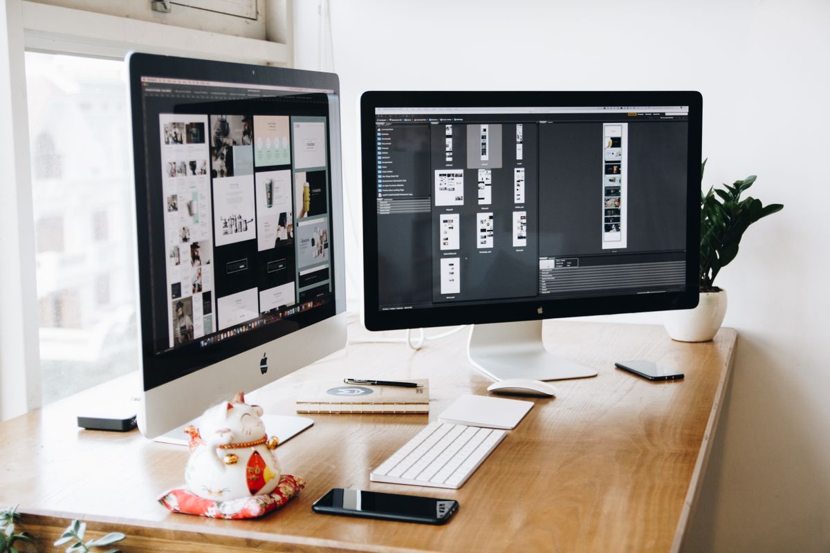 Website layouts open on a designer's dual-monitor desk